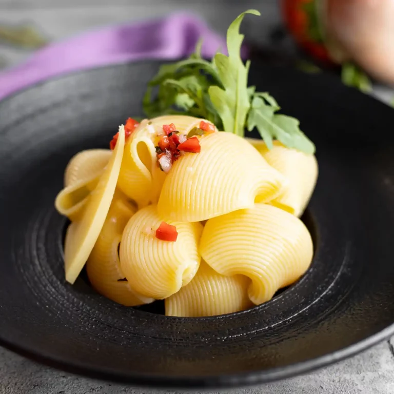 Close up di conchiglie di pasta con insalata di pomodoro e cipolla a cubetti